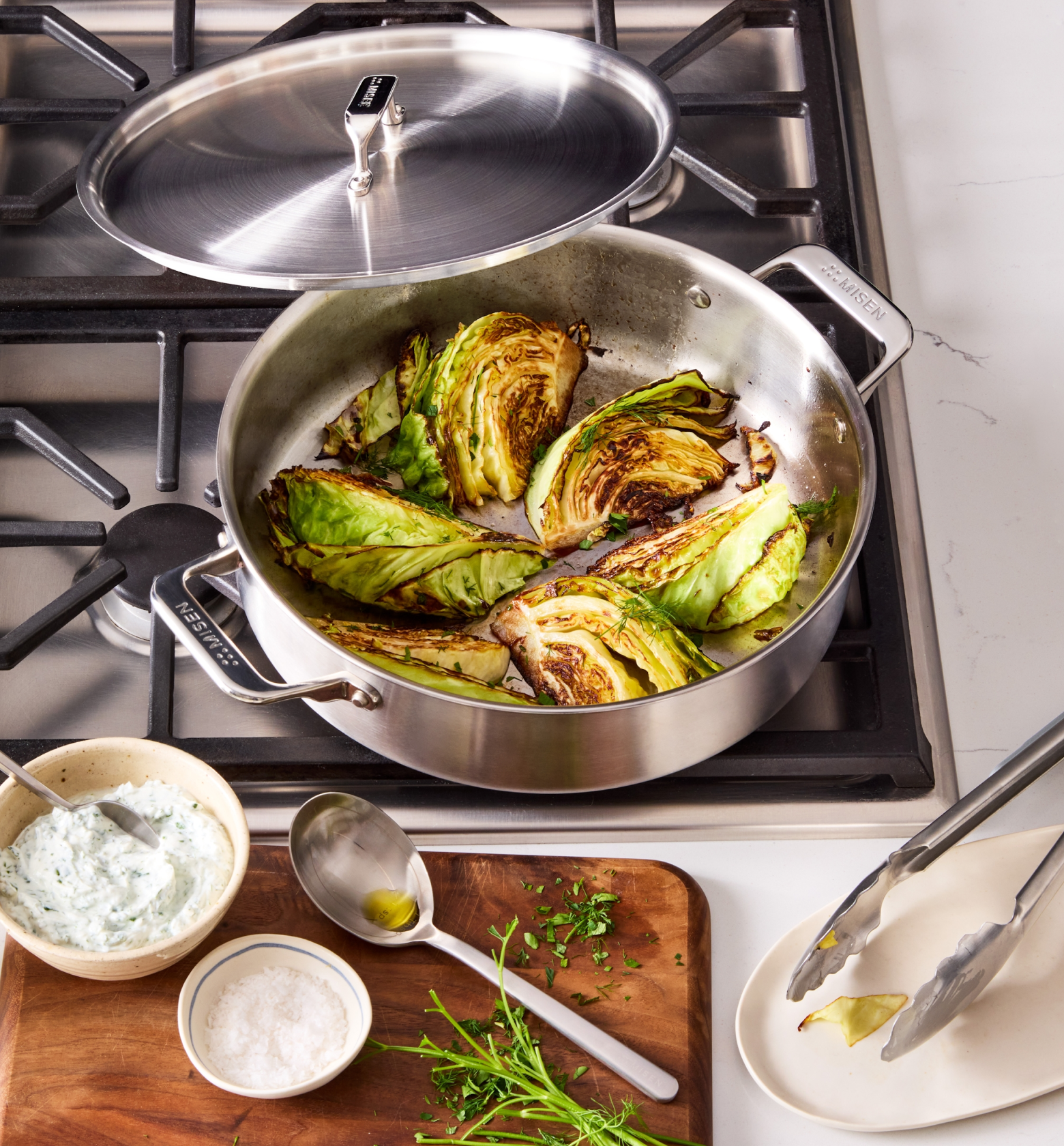 Seared cabbage wedges in Misen stainless steel braiser pan on gas stovetop with herb sauce